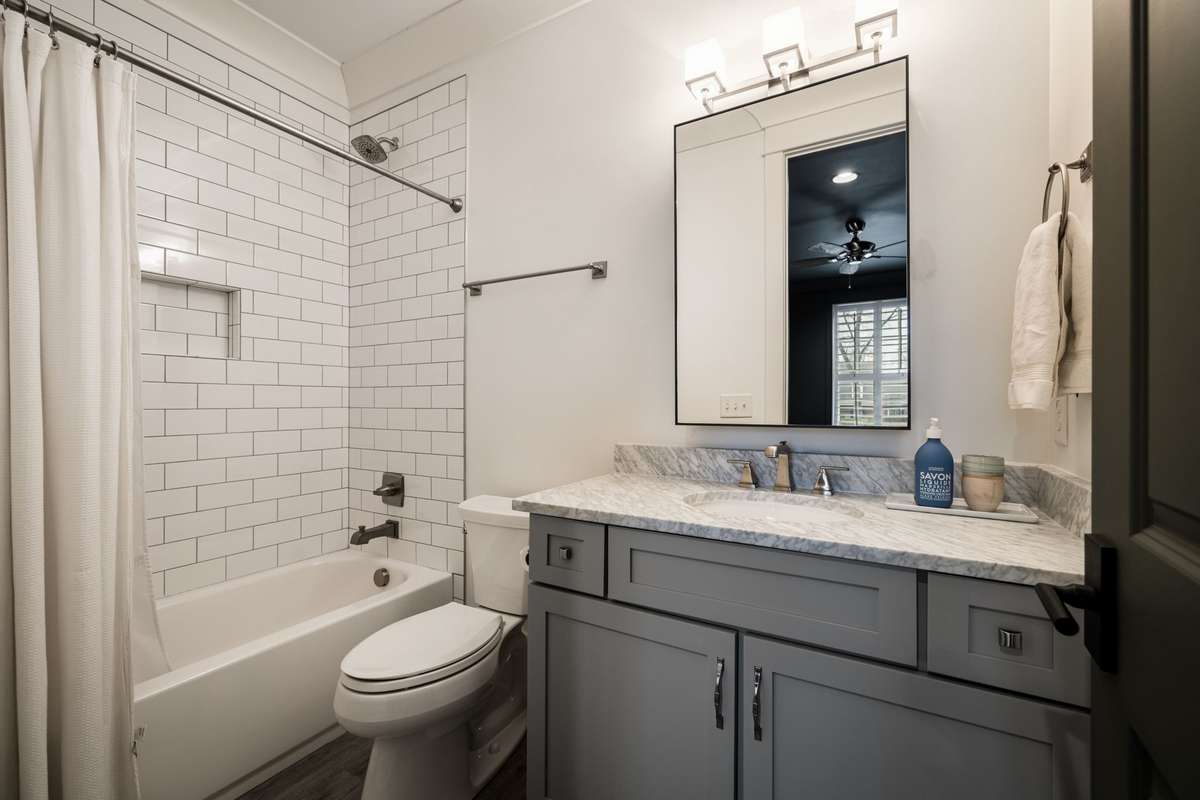 En suite bath with marble countertop and tub-shower combination