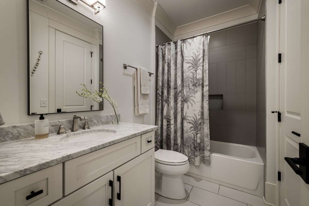 Hall bath with marble countertop and tub-shower combination