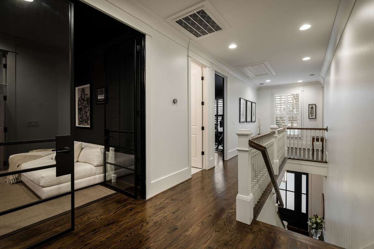 Upper-level hallway with hardwood floors and glass-door office entry