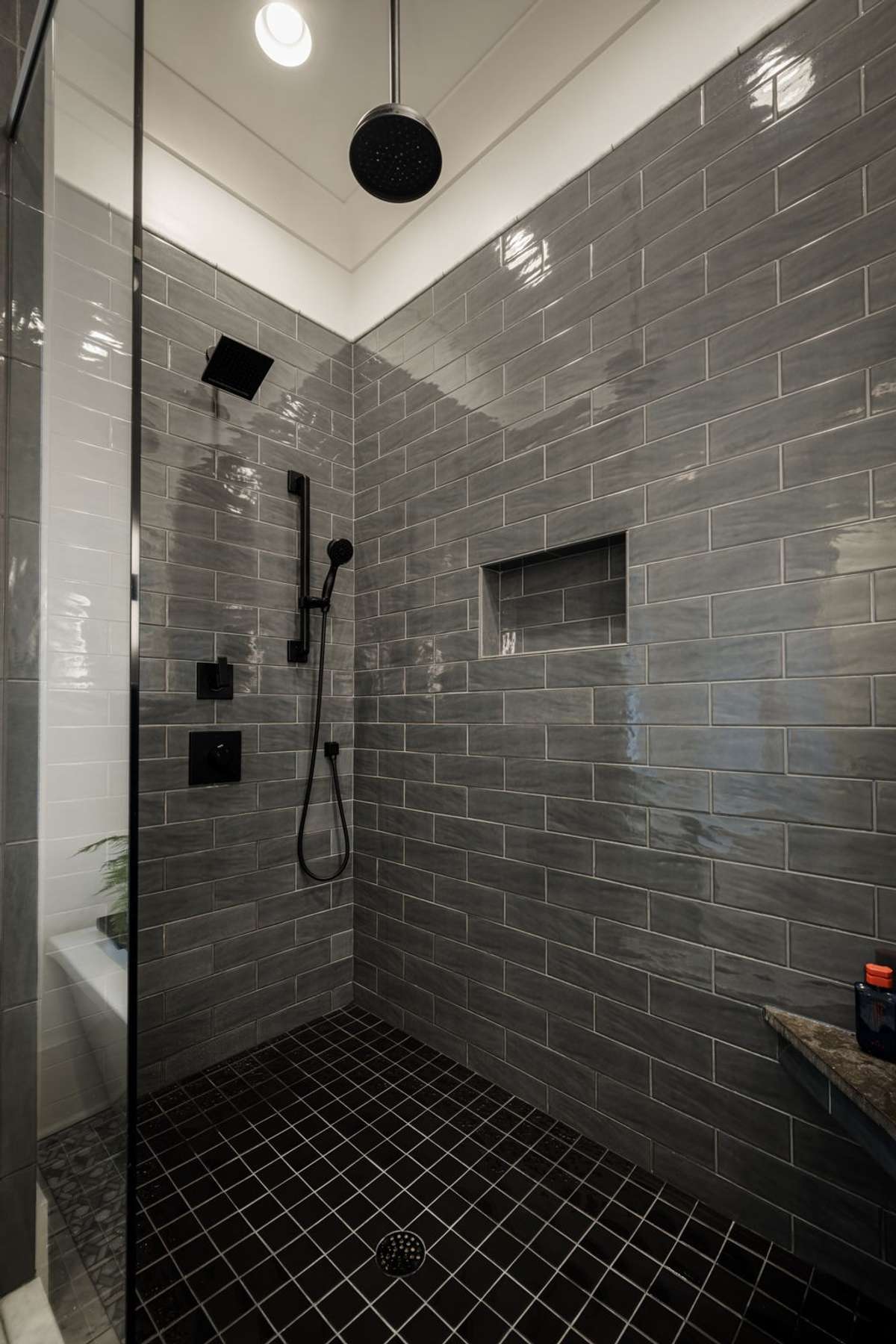 Walk-in shower with dual fixtures, tile, and built-in niche