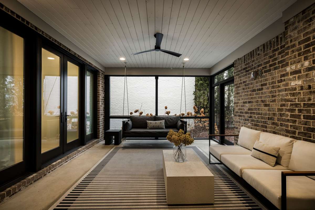 Screened porch with lounge seating, swing, and ceiling fan