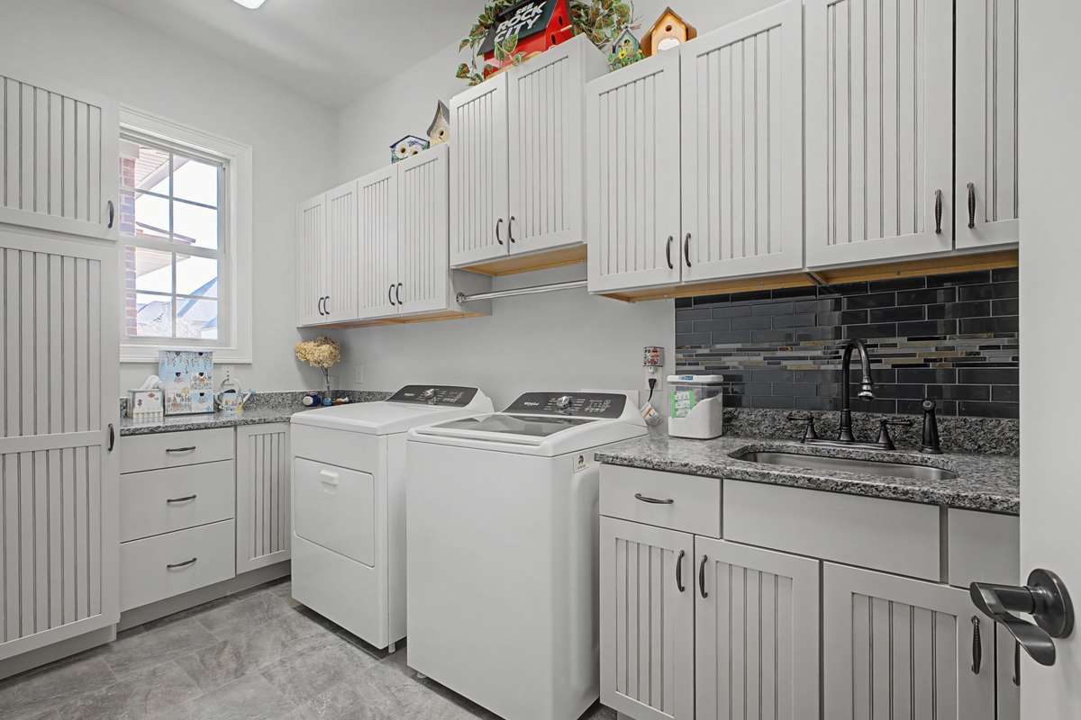 Spacious laundry room with plentiful custom cabinetry and sink