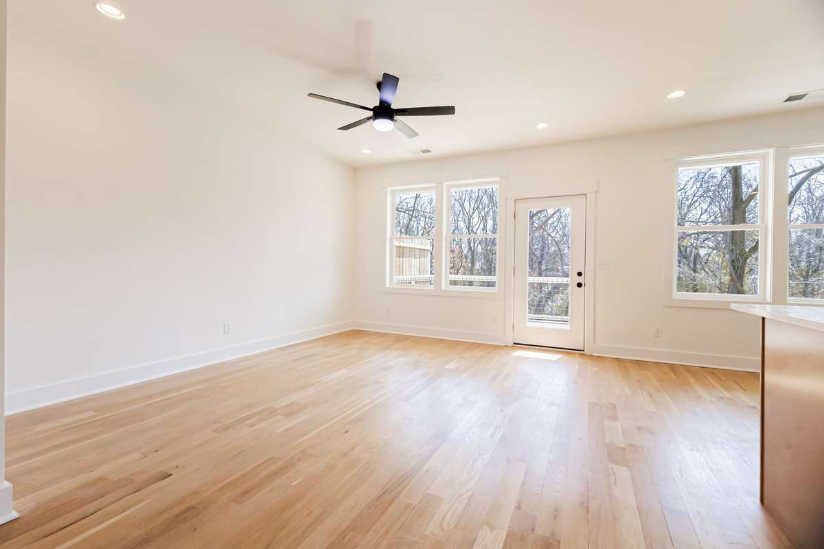 Spacious living room leading to private backyard balcony and kitchen.