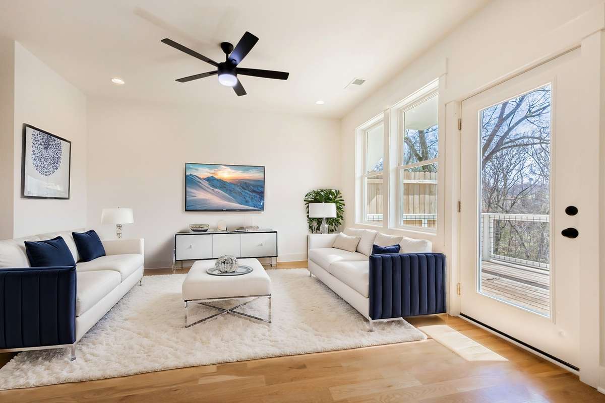 Virtually staged photo of spacious living room leading to private backyard balcony and kitchen.