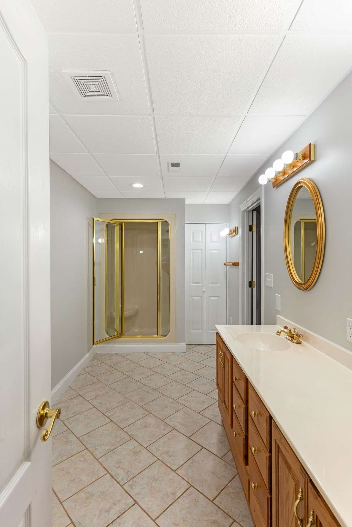 Basement guest bathroom with tile floors and solid surface vanity.