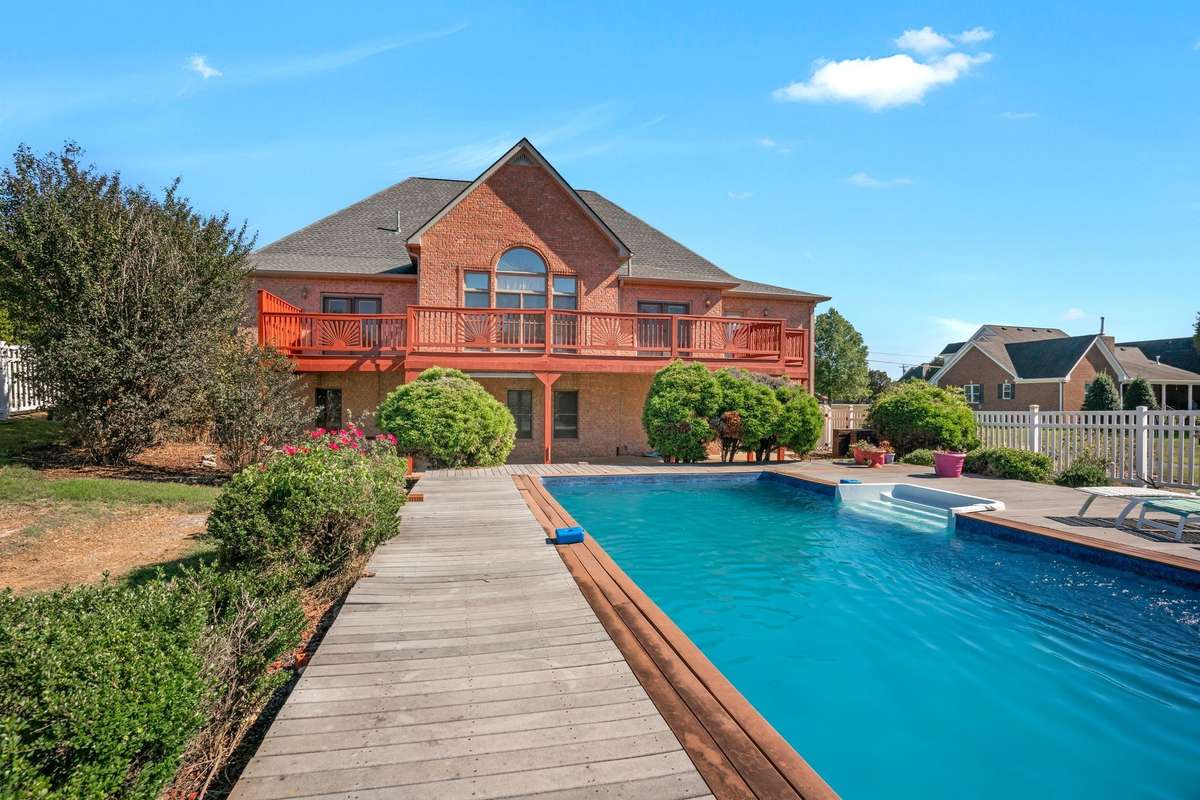 Back of home boast beautiful landscaping, large main level deck, and decking around pool.