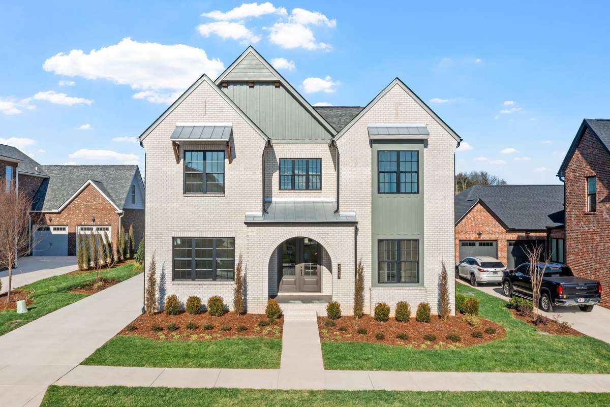 Front Exterior Elevation in a light brick color & a beautiful arched entry into front covered porch