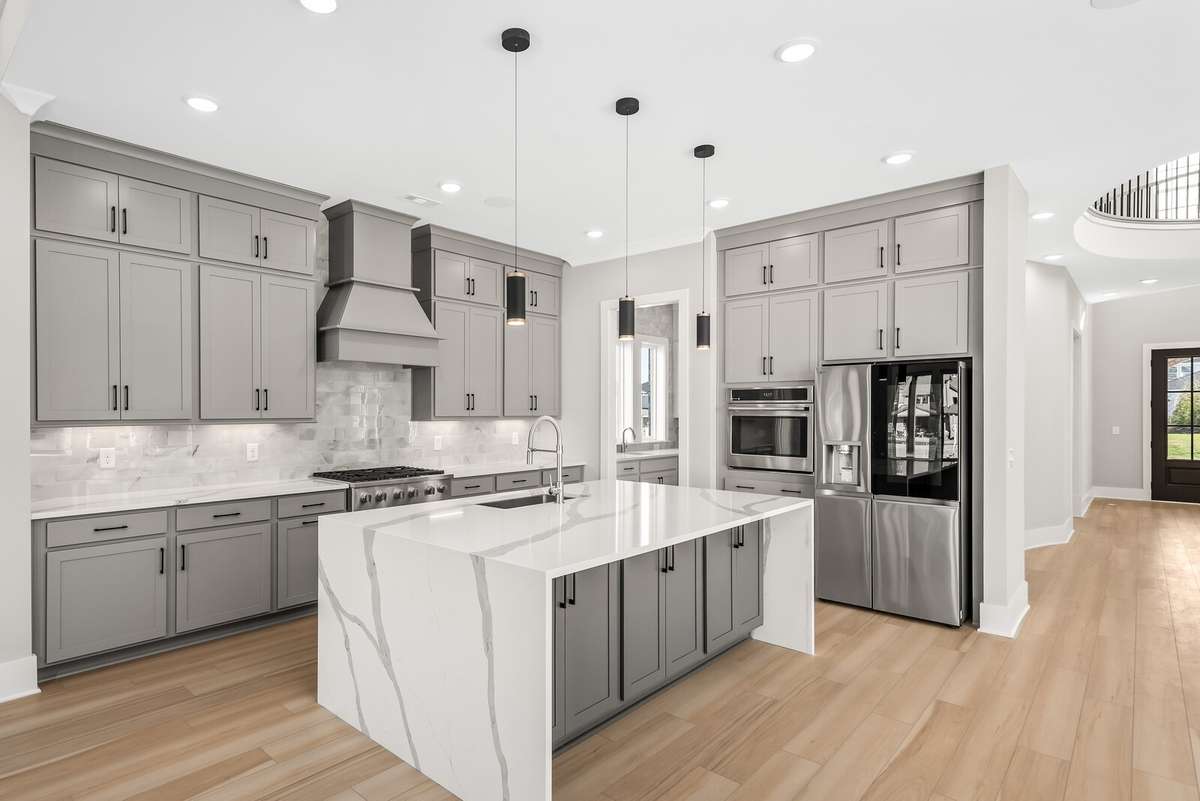 Gorgeous Upgraded Arabescato Quartz Waterfall Counter on large kitchen island with 3 pendant lights