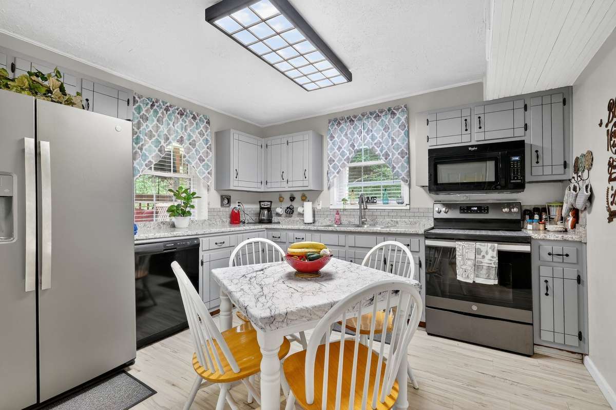Main kitchen with stainless and black appliances, new flooring and freshly painted cabinets.