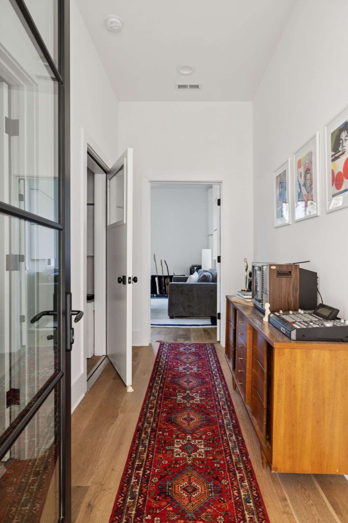 The music studio features a beautifully styled hall with a half bath to the left and an iso booth just past the bathroom