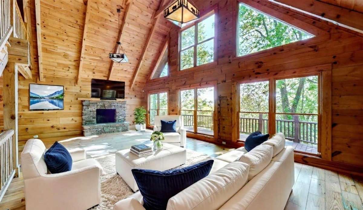 The virtually staged Living room shows off the open floorplan with massive windows. Enjoy the views all the way through the kitchen as well.  The wood burning fire place offers rustic charm and warm cozy evenings.