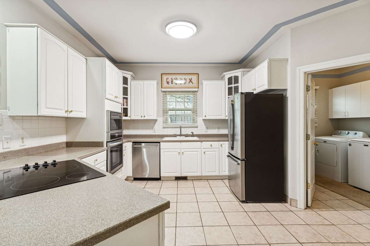 Kitchen has a classic tiled backsplash, white cabinetry with decorative glass corner pieces and built-in oven & microwave. 2409 Amber Glen Court, Murfreesboro, TN 37128