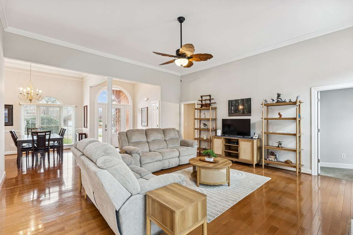 This light-filled living room showcases beautiful hardwood flooring, elegant crown molding, and a graceful arched entry that adds architectural charm! 2409 Amber Glen Court, Murfreesboro, TN 37128