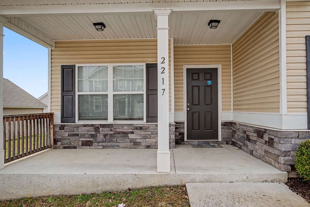 Relaxing covered front porch with stone accents and space for seating — perfect for enjoying morning coffee or evening downtime.