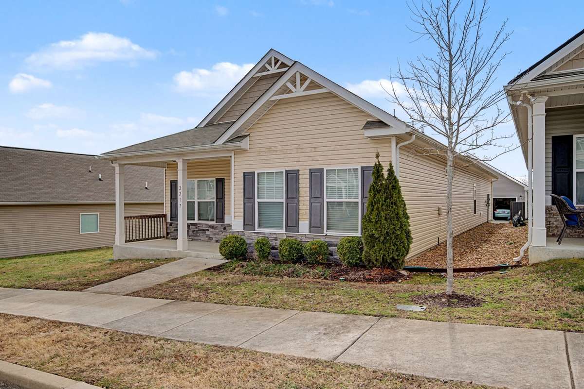 Spacious front façade showcasing ample natural light through large windows and a covered entry. Well-positioned lot with defined walkway and open sightlines.