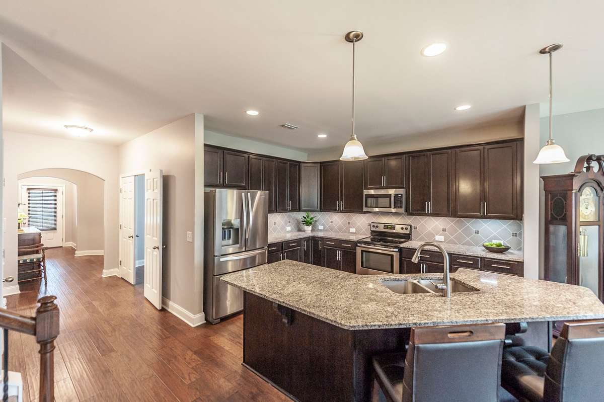 This beautiful open kitchen offeres a double stainless steel sink and appliances, stone back splash highlighted by the under cabinet lighting. Pendant and extra recessed lighting make this a bright work space and and entertainment area.