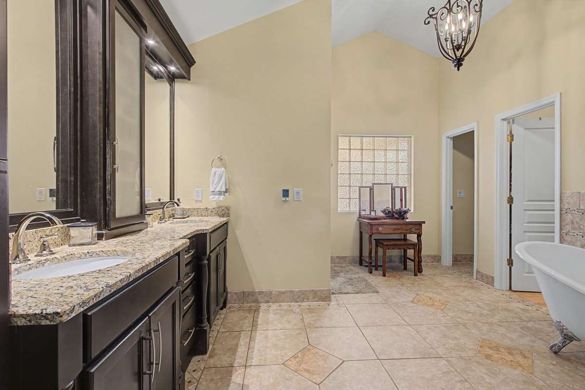 Master bath with ceramic tile, dual sinks, walk-in shower, claw foot tub, and walk-in closet