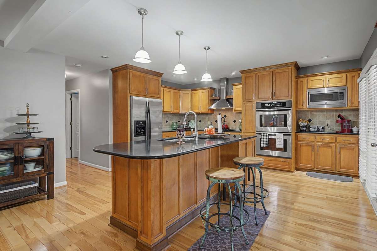Rich wood cabinetry with granite countertops and a spacious center island with bar seating. Stainless steel appliances, including a double wall oven, built-in microwave, dishwasher and French door refrigerator. All remainng.