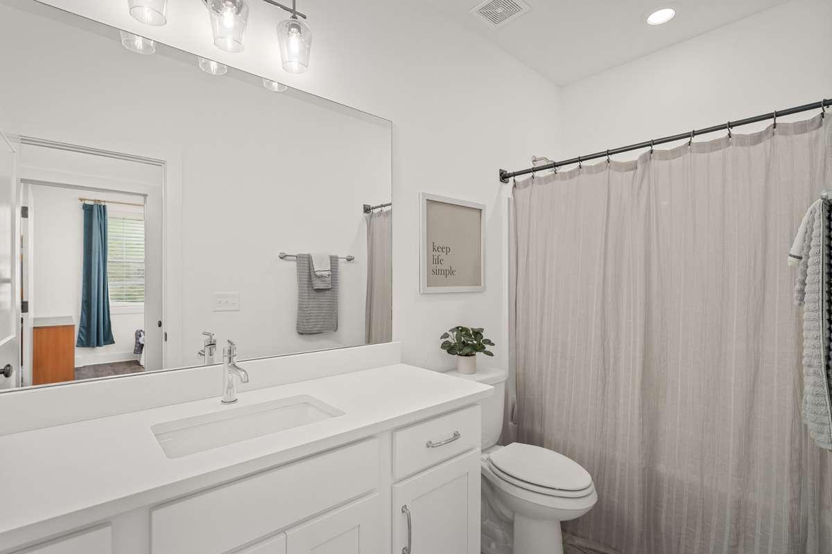 Another full bath located beside of the secondary room on the main level. It has a long cabinet with extra storage, quartz countertops and shower.
