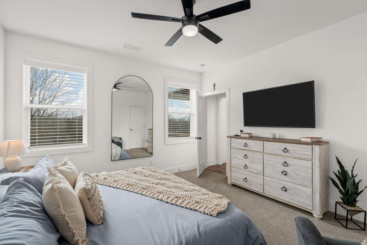 What a nice primary suite with a fan and located off to the side of the home. It has a great walk-in closet and a primary bath attached.