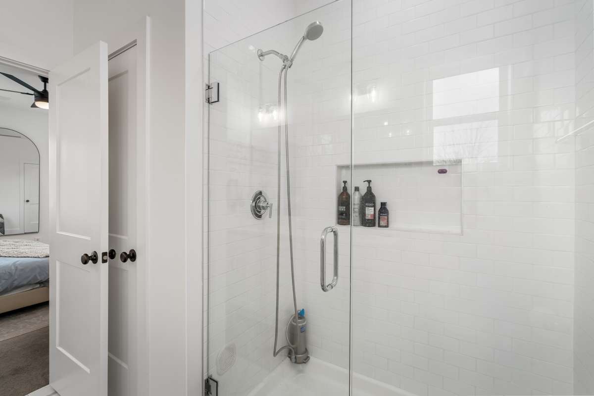 This walk-in shower is huge with a glass front door and tile the ceiling.