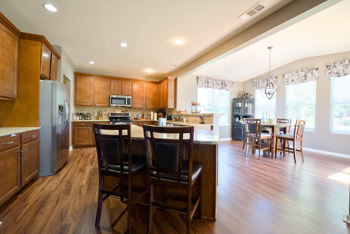 Kitchen with granite countertops opens to sunroom and living room with fireplace