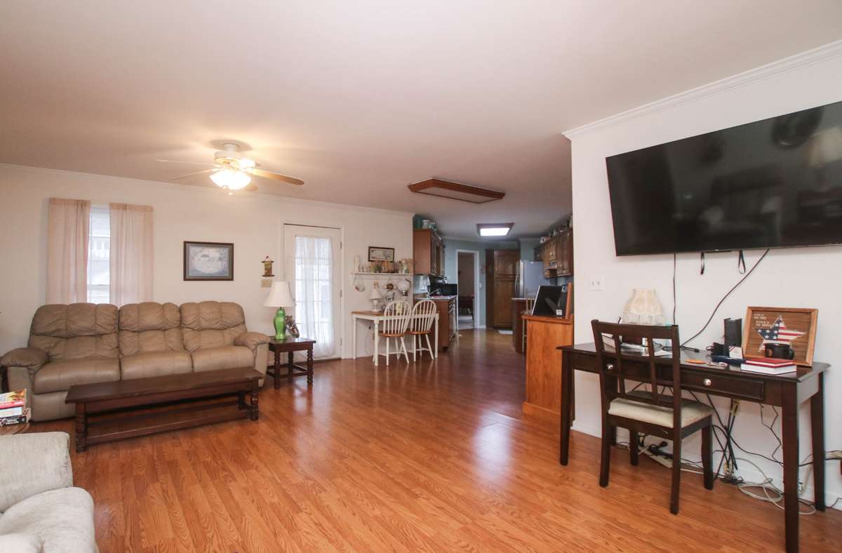 The other side of the room shows access to the kitchen and the door leading to the back deck