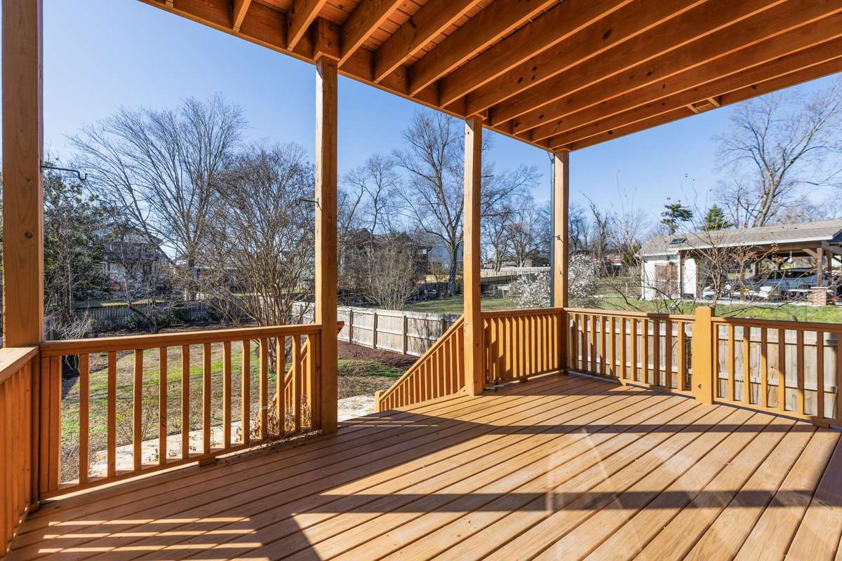 Back covered porch off main level leading down stone patio and sidewalk to fence entrance.