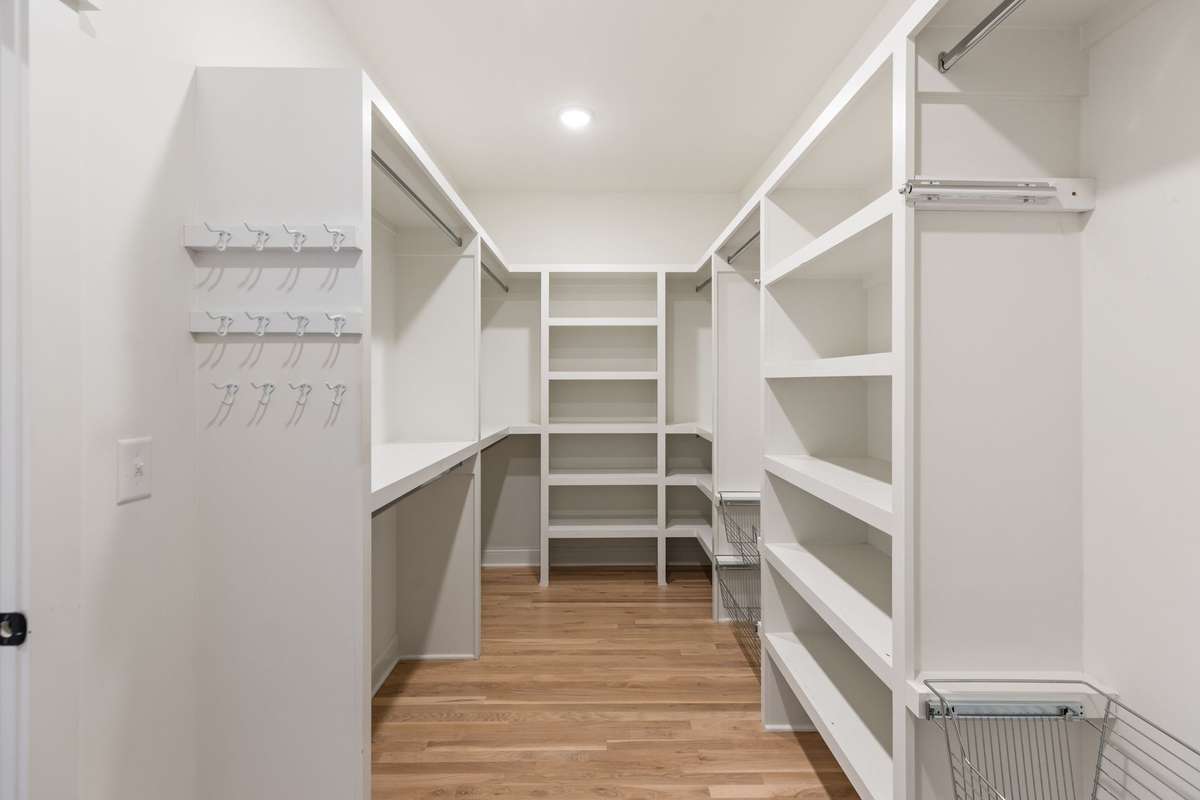 Large primary closet with shelving, hooks and multiple storage features!