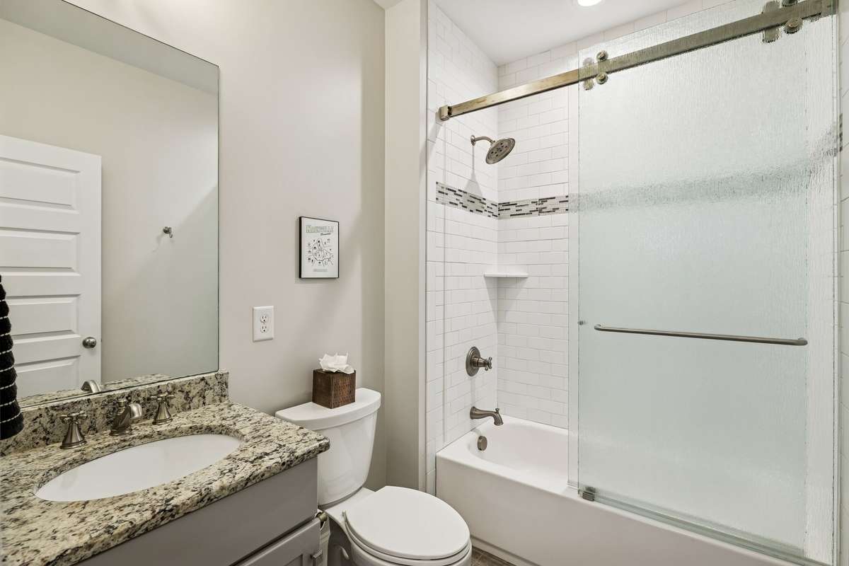 Secondary bathroom with granite countertops, updated fixtures, and a clean tile surround.