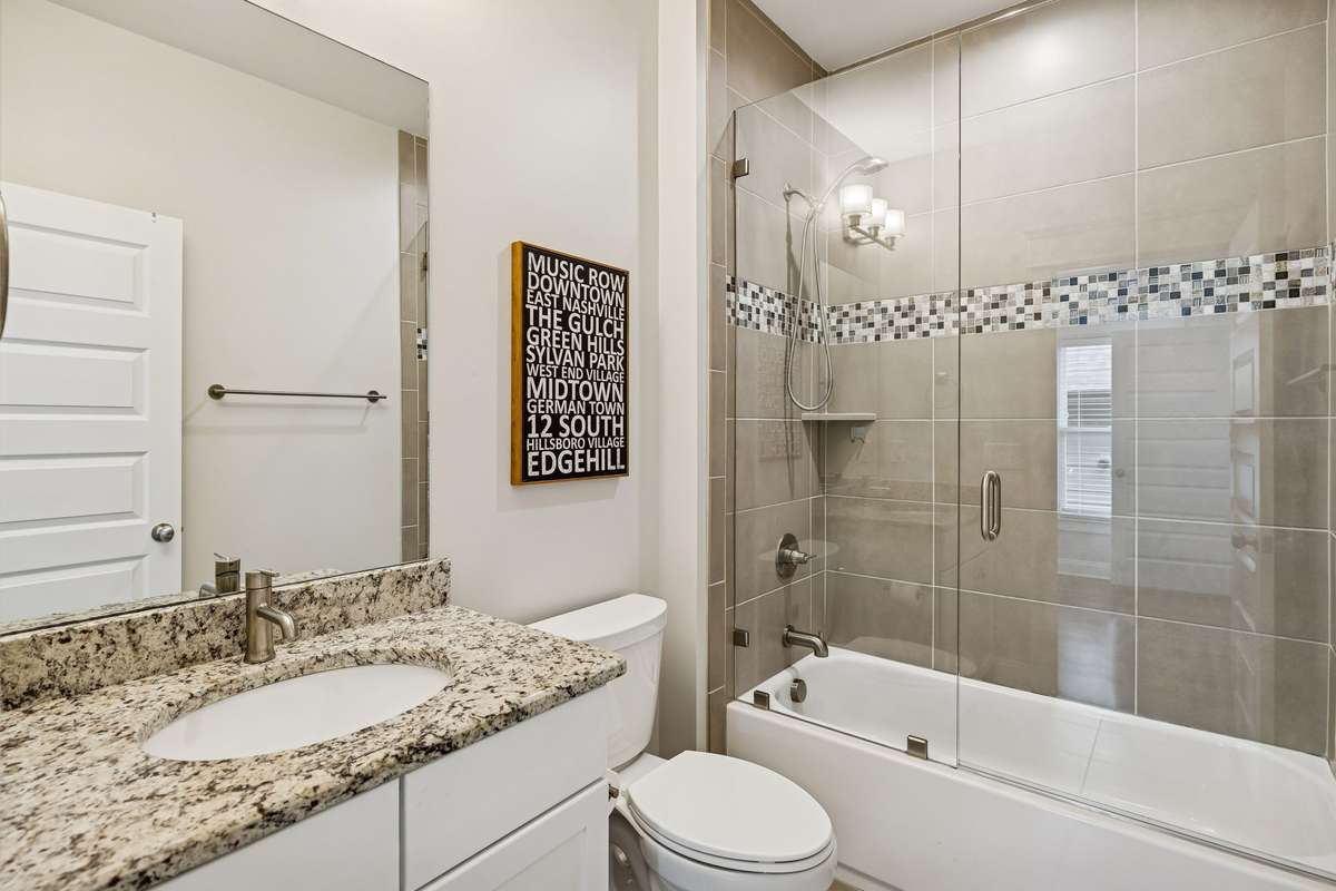 Additional full bathroom with tile surround, glass enclosure, and modern finishes.