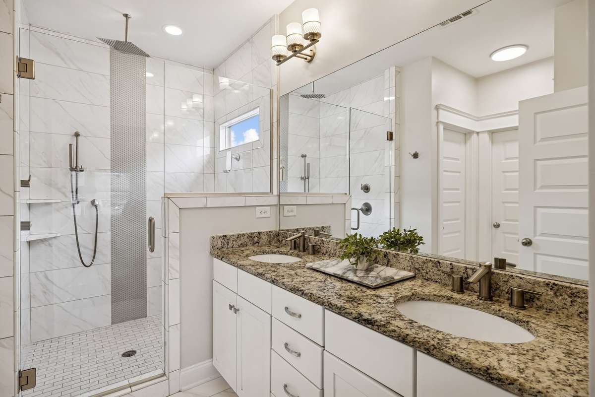 Primary bathroom with dual vanity and large tile shower with rain head.