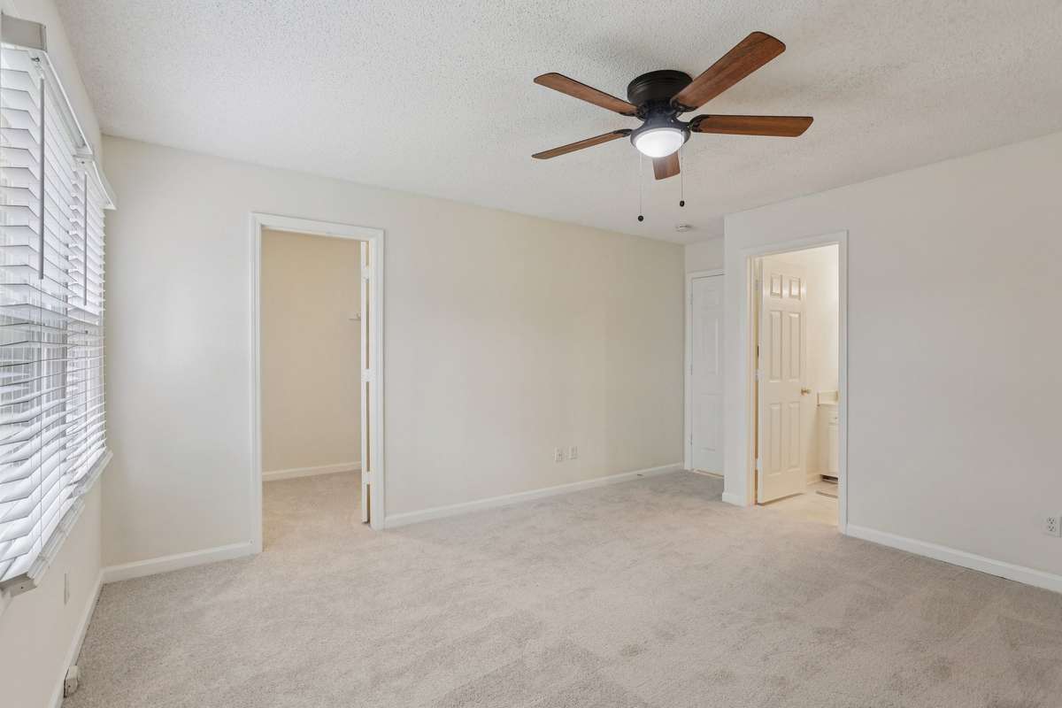 Ceiling fans and window blinds in the primary bedroom.
