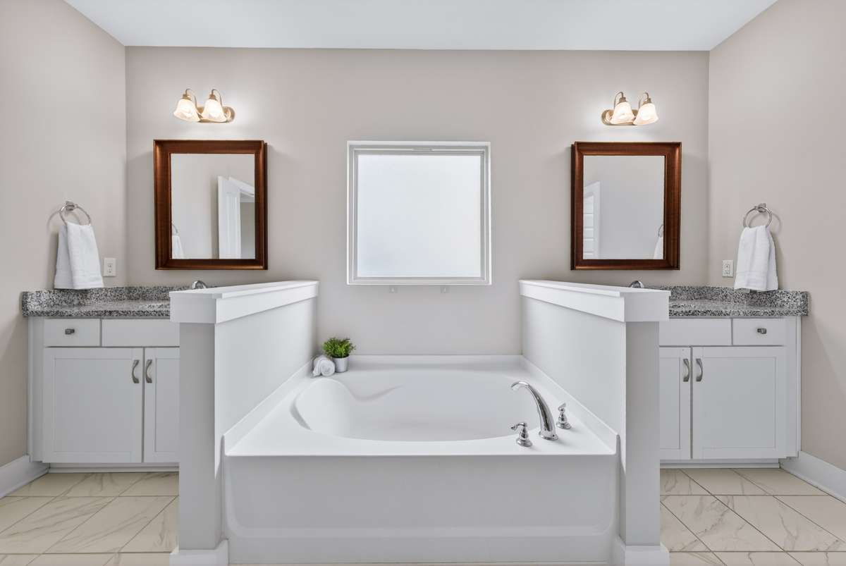 The bathroom features a soaking tub alongside a his-and-hers vanity, offering both comfort and everyday convenience.