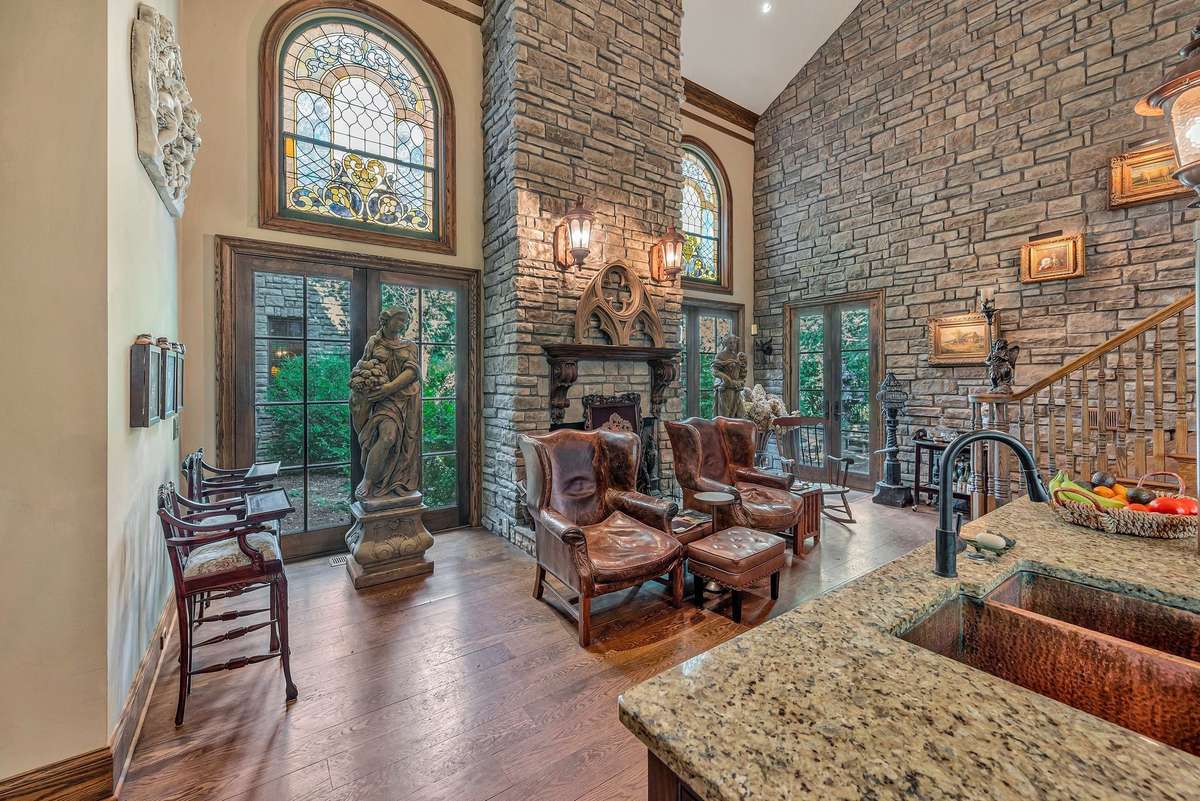 The stone fireplace in this gothic kitchen is grand and full of presence, Rising above the fireplace are arched stained glass windows. which draws your eyes upwards emphasizing tall ceilings and architecture,