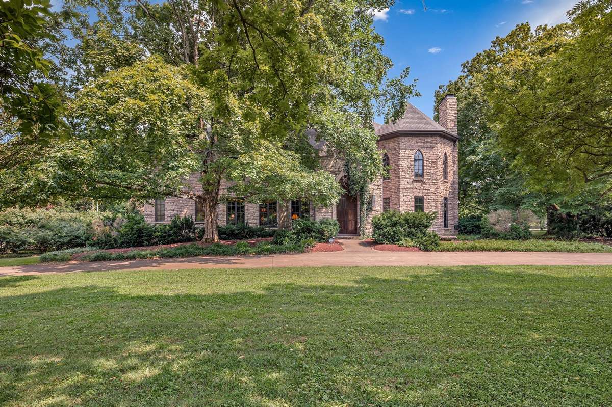 Perched proudly on a corner lot, this stone Gothic estate commands attention with its towering turret, grand arched doors, arches, balconies, rich, wood paneling, oversized gorgeous winding staircase, soaring ceilings and serene private pool