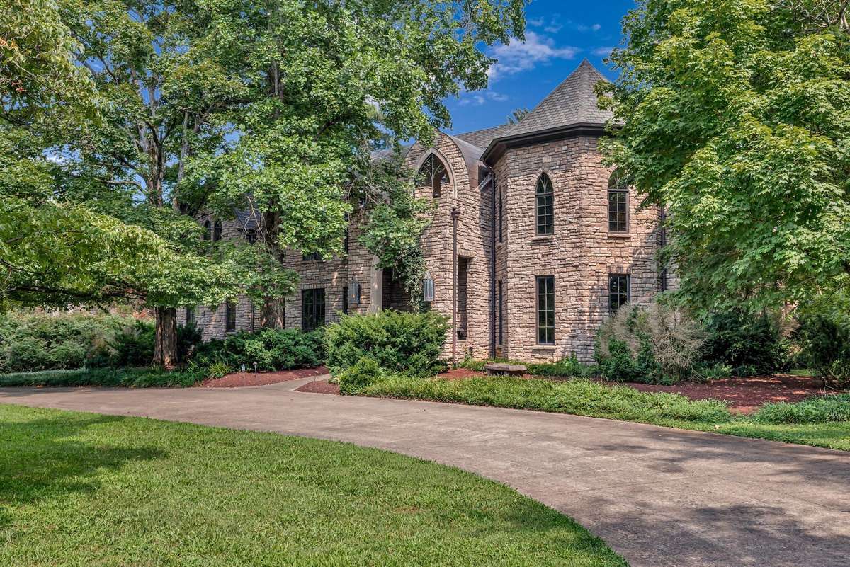 A grand horseshoe driveway elegantly curves through the greenery leading to this majestic Gothic home. Stone pillars offers a regal approach to the entrance and exit from the street for guests. On the side street there is a two car garage.