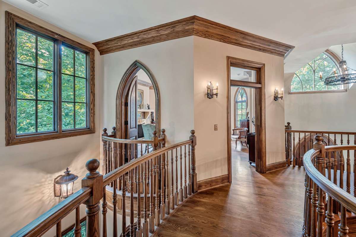 Upstairs hallway leading to the office with Romeo and Juliet balconies and arched door.