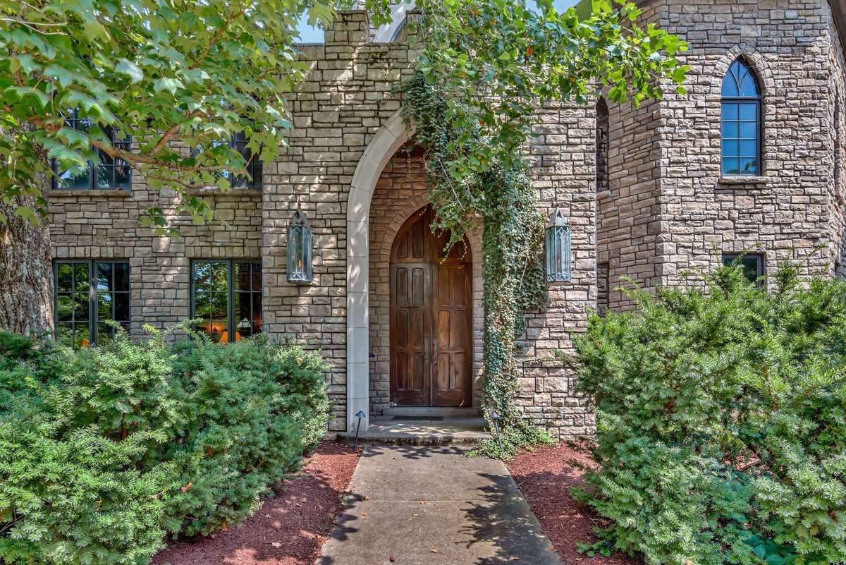 Storybook-romantic, Gothic style grand front door framed by greenery and timeless stonework/ limestone