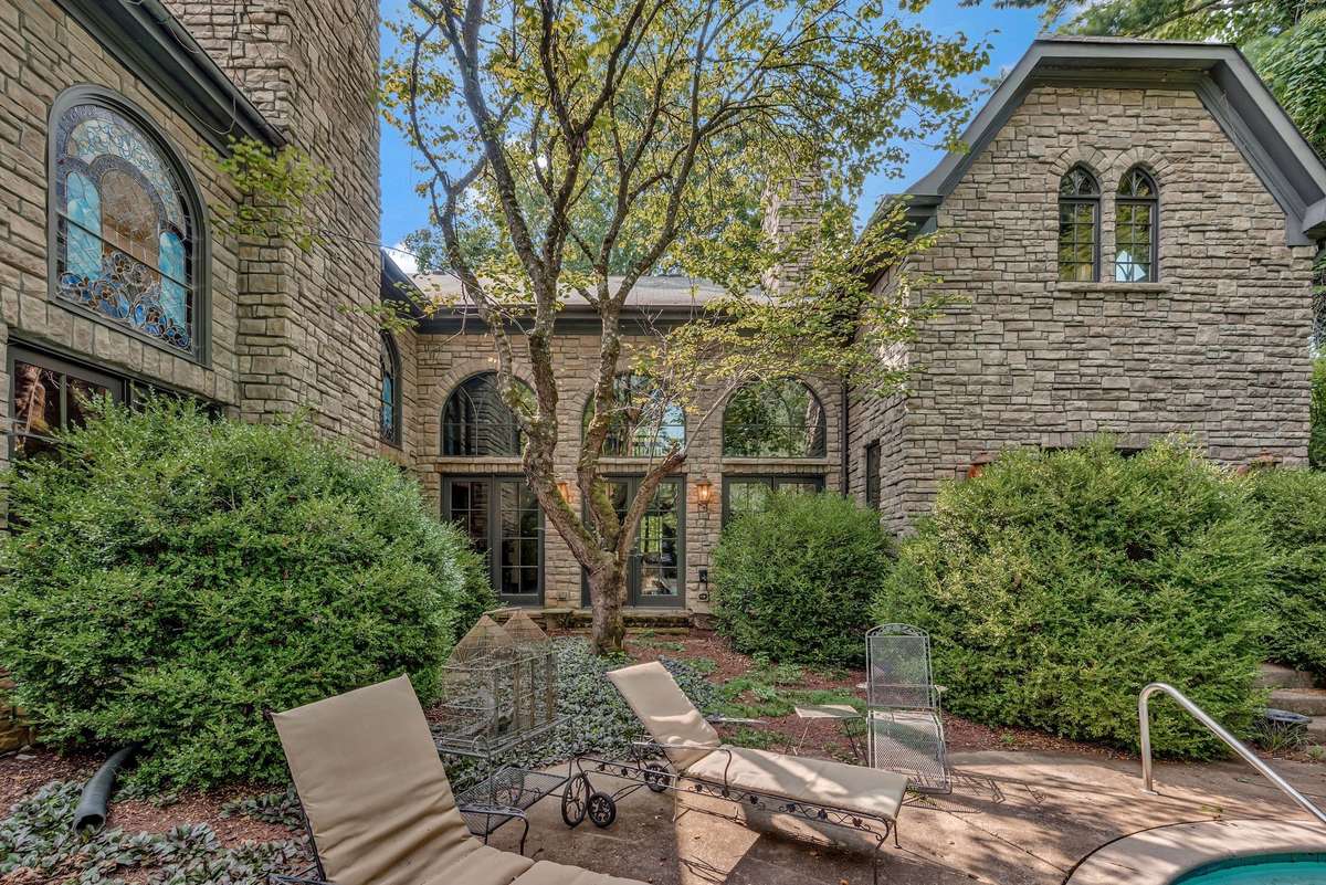 An outdoor fireplace is nestled in the u-shaped courtyard. The redbud in the center of the u-shape blooms its heart out with vibrant purple pinkish flowers each spring that you can see through all the windows on the back of the house.