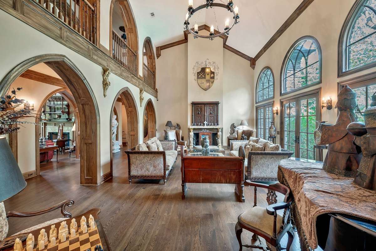 A grand, dramatic fireplace is a centerpiece to the Great room as arched windows and arched openings frame the space. French doors open up to the pool which makes it great for entertaining. The house makes a u-shape on the backyard framing the pool