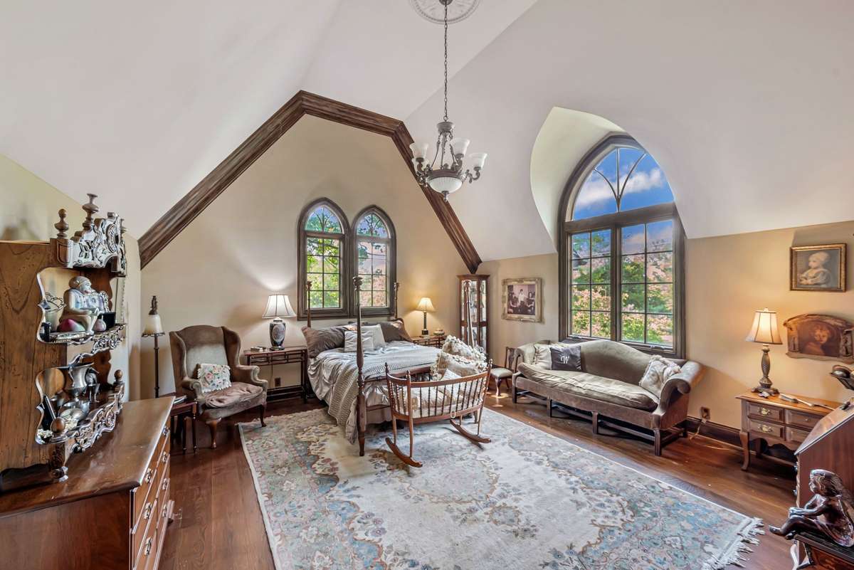 This bedroom is a dramatic calming retreat with soaring ceilings and arched windows