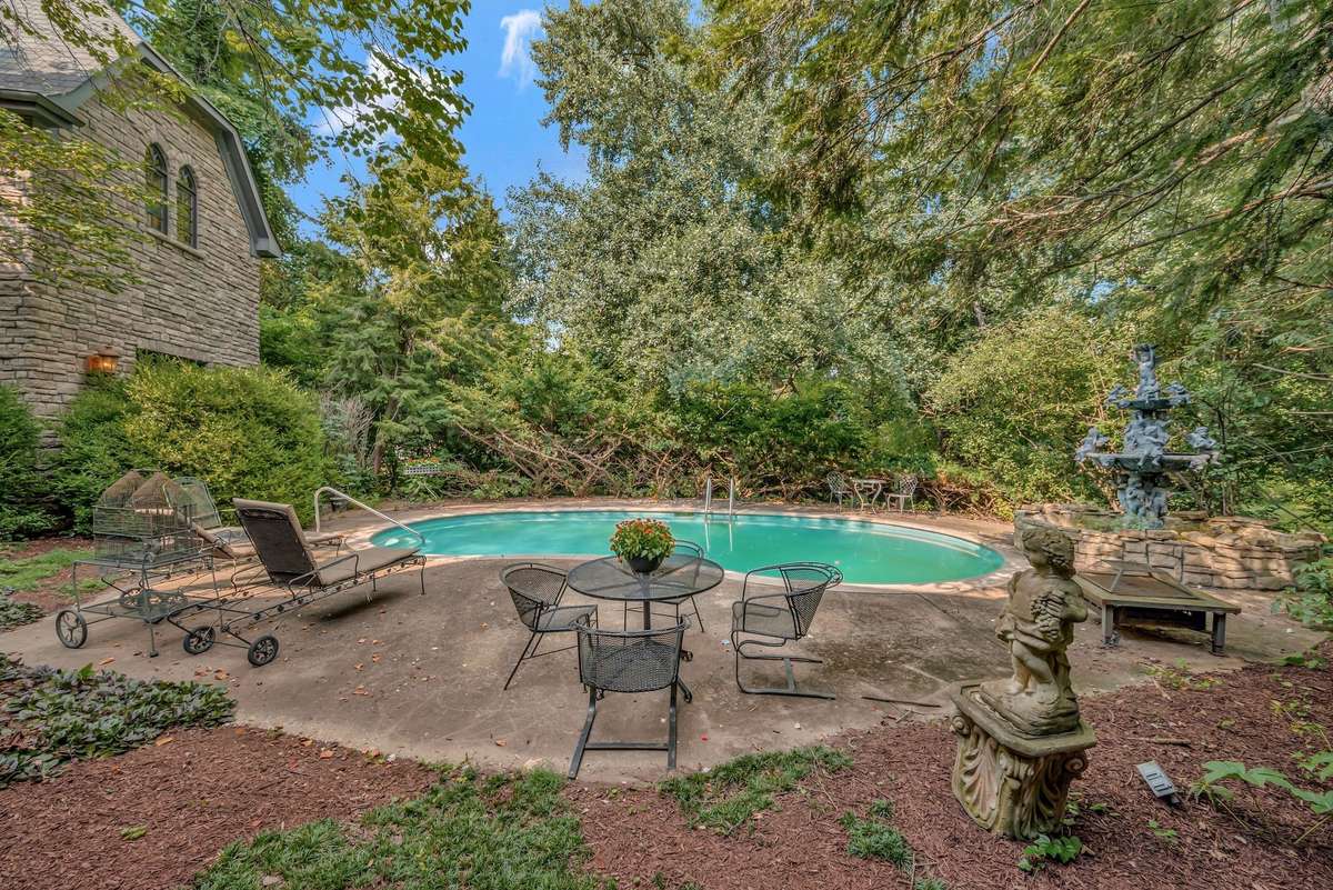 Tucked behind the towering stone walls of this estate the pool of this home feels like a hidden sanctuary framed by aged stone walls and mature trees that can tell stories with their age, shape, scars and setting.