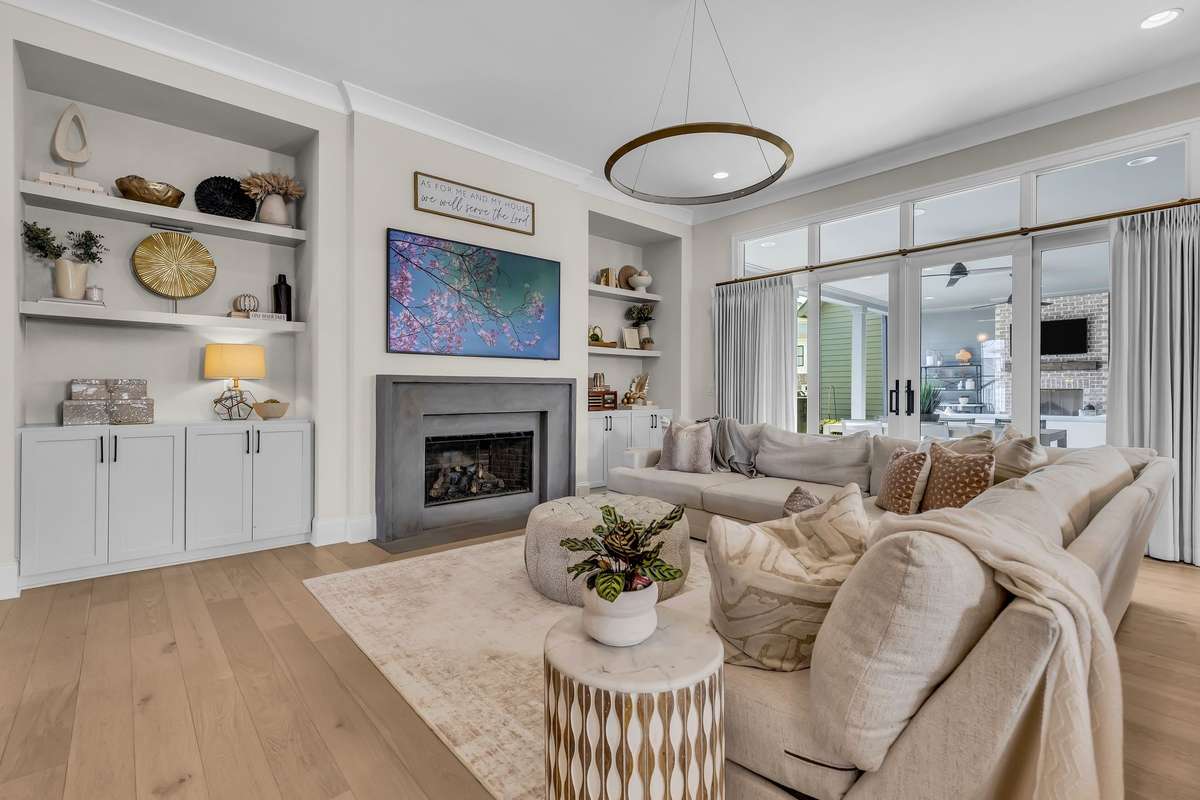 Large Living Room with built in bookshelves, fireplace, and surround sound that opens to kitchen and views of the covered patio.
