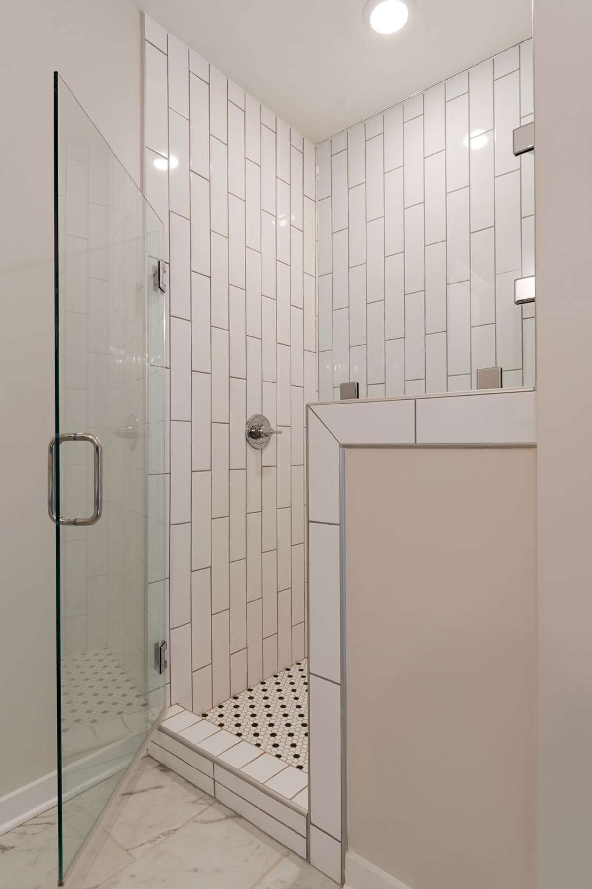 A beautiful tiled, white shower with high end hardware