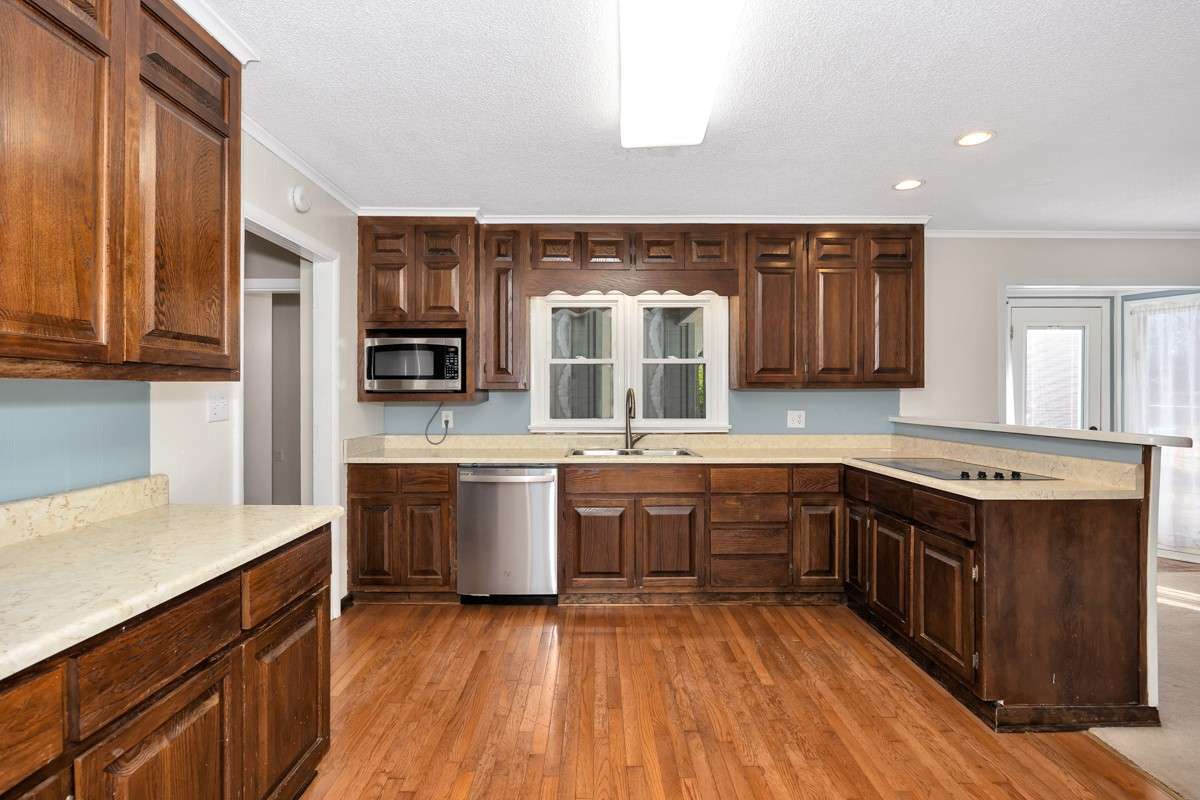 Kitchen- wood flooring, crown molding, wood cabinetry, stainless steel appliances, recessed lighting