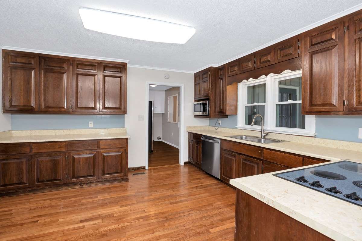 Kitchen- wood flooring, crown molding, wood cabinetry, stainless steel appliances, recessed lighting