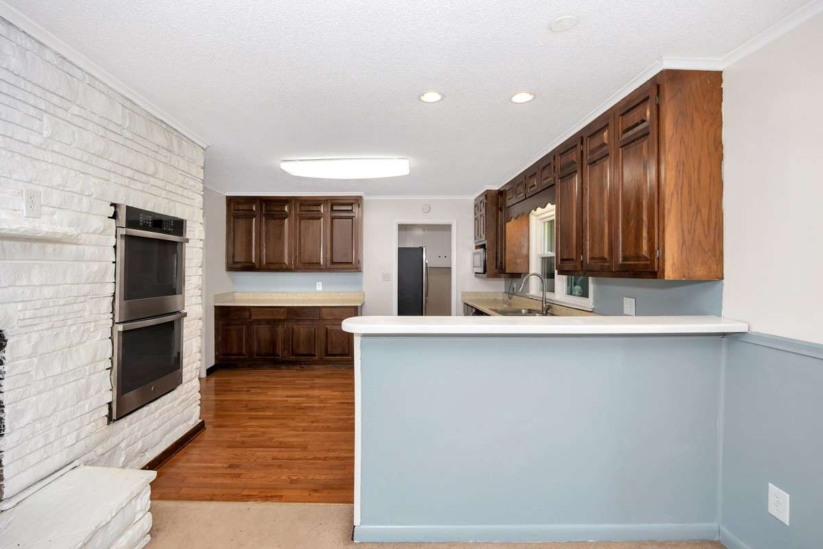 Kitchen- wood flooring, crown molding, wood cabinetry, stainless steel appliances, recessed lighting