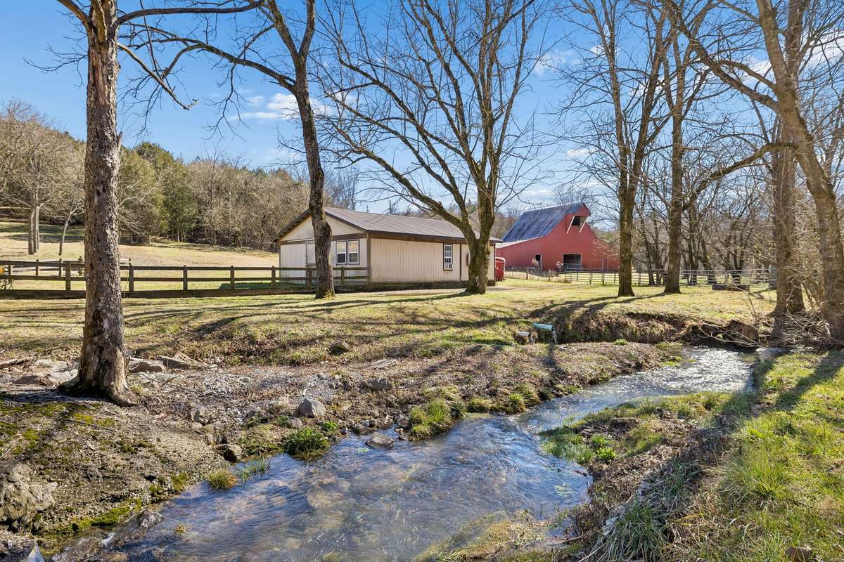 The horse barn is the tan color building (the red barn is NOT part of this property). This clear creek is a beautiful addition to this property!