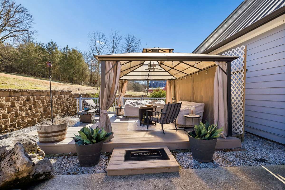 The gazebo (with furniture currently covered for the winter). Notice the stone retaining wall around the back yard.